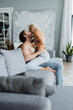 © LIGHTFIELD STUDIOS - side view of cheerful couple kissing on couch