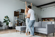 © LIGHTFIELD STUDIOS - woman raising hands while dancing with boyfriend in living room