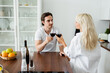 © LIGHTFIELD STUDIOS - young man and woman clinking glasses of red wine in kitchen