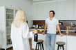 © LIGHTFIELD STUDIOS - happy man looking at blonde woman with bottle of wine in kitchen