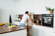 © LIGHTFIELD STUDIOS - man flirting with happy girlfriend smiling in kitchen