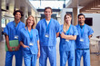 Portrait Of Multi-Cultural Medical Team Wearing Scrubs Standing Inside Hospital Building