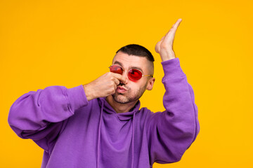 Canvas Print - Photo of funny millennial brunet guy dance wear eyewear purple hoodie isolated on yellow color background