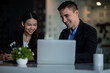 © David - Business people working together. Serious businessman with laptop talking to a businesswoman with papers and tablet. Business partners have a successful meeting in the modern office.