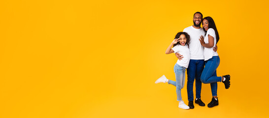 Wall Mural - African American man hugging his wife and excited daughter