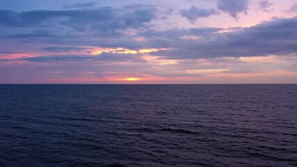 Wall Mural - View from above, flying over water, stunning aerial view of a dramatic, cloudy sunrise with a bright sun rising over a calm water. Sardinia, Italy.