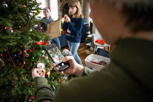 Boy With Camera Phone Photographing Ornament On Christmas Tree
