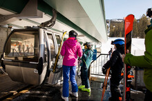 Family With Skis Waiting For Ski Lift Gondola At Ski Resort