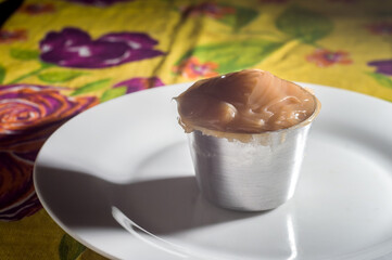 dulce de leche, in a small pot on a white plate, selective focus