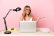 © luismolinero - Young student woman in a workplace with a laptop over pink background holding copyspace imaginary on the palm to insert an ad