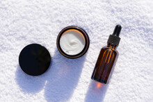 Open Amber Glass Jar And Amber Glass Dropper Bottle With Black Lid The Appearance Of The Cream Texture Against The Background Of A White Towel. Skincare Products , Natural Cosmetic.