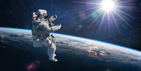 Poster - Astronaut in outer space on orbit of Earth planet. Sky and clouds. Spacewalk with stars. Sun light on background. Elements of this image furnished by NASA