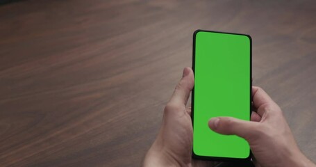 Wall Mural - Slow motion man hand using smartphone with green screen over black walnut wood table