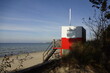 Red and white wooden lifeguard cabin with a stair on an empty sandy beach in Pirita. Empty beach with no people on a sunny day. Tallinn, Estonia. October 2021
