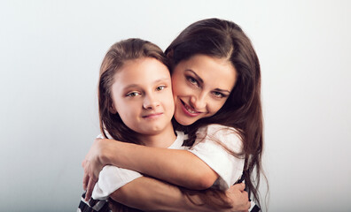 Wall Mural - Happy beautiful mother hugging her smiling daughter with love on studio background