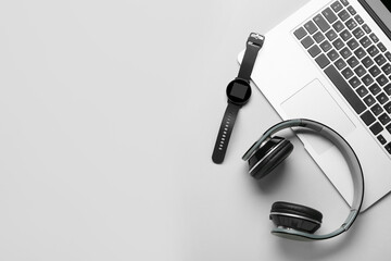 Smart watch, headphones and laptop on grey background