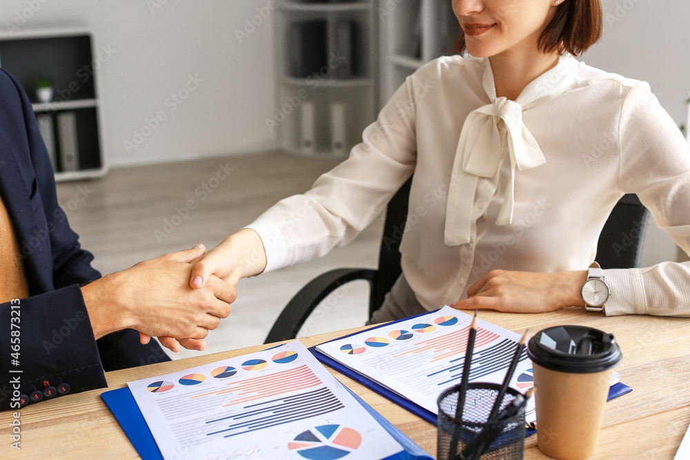 Business co-workers shaking hands at table in office