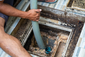 Man Emptying household septic tank. Cleaning and unblocking clogged drain at home.
