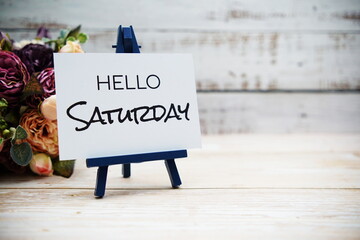 Canvas Print - Hello Saturday text with flower bouquet on wooden background