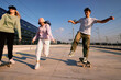 © chika_milan - Three excited teenagers spend time in the urban exterior. They are running and skateboarding.