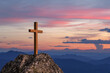 Silhouettes of crucifix symbol on top rock mountain with bright sunbeam on the colorful sky background