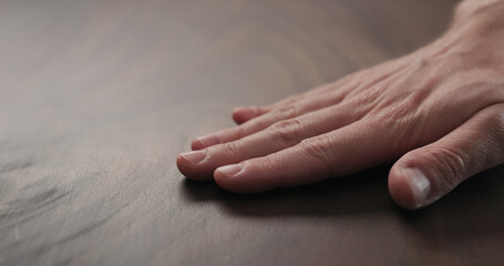 Poster - man hand checking toned walnut table surface with oil finish