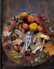 Wiccan witch altar, wheel of the year on dark background. small skeleton, magic things, pumpkins candle. esoteric ritual for Samhain sabbat. autumn season. top view