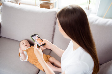 Wall Mural - Photo of positive blogger influencer mother hold phone take little son picture lay divan wear casual outfit home indoors