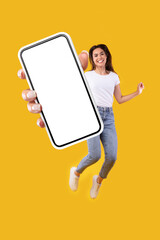 Wall Mural - Woman showing white empty smartphone screen and jumping up high