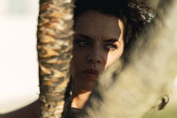 Canvas Print - Closeup shot of a female with a suspenseful gaze posing near a tree