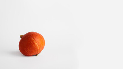 Wall Mural - Hokkaido pumpkin on a white background. The pumpkin is located in the lower left corner. Front view