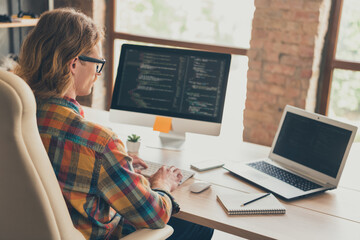 Profile side photo of young man work online computer monitor it specialist website coding sit desk indoors