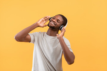 Wall Mural - Best music. Happy african american guy in wireless headphones enjoying his favorite songs and smiling