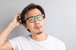 © bennnn - Asian man wearing eyeglasses with surprise and wonder expression on grey background.