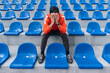 fan is disappointed with the loss of his favorite team. One person in the stadium. disappointed upset young fan sitting on the tribune