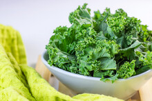 Fresh Green Curly Cabbage Or Kale Salad Leaves Cut In The Bowl On Light Background On The Table In The Kitchen.