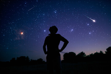 Wall Mural - silhouette of a man enjoying countryside under the starry skies.