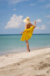© saulich84 - young fashionable woman in a yellow hat dress and sun glasses is posing on beach in summer on vacation
