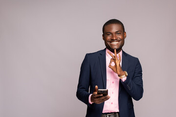 Wall Mural - happy african businessman holding his phone does the okay gesture