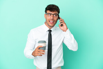 Wall Mural - Business caucasian man isolated on blue background holding coffee to take away and a mobile