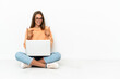 © luismolinero - Young woman with a laptop sitting on the floor with surprise facial expression