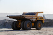 © alexhitrov - Industrial work in an open pit coal mine. A large yellow dump truck is carrying coal soil through the quarry. Open pit coal mining.