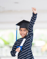 Wall Mural - Portrait of a cute happy Asian school kid graduate with graduation hat and a diploma isolated on white background. Education Concept Stock Photo