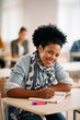 © Drazen - Happy black woman writes in notebook while having lecture at university classroom.