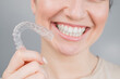 Close-up portrait of a woman putting on a transparent plastic retainer. A girl corrects a bite with the help of an orthodontic device