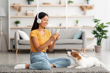 Wall Mural - Cheerful asian woman taking photo of her cute dog