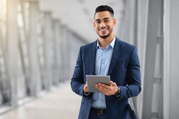 Smiling Young Middle Eastern Man With Digital Tablet Posing At Airport Terminal