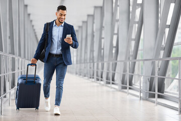 Online Check In. Handsome Arab Man Walking In Airport And Using Smartphone