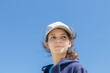 Natural face portrait of a young caucasian woman, no retouching skin, no color correction. Close-up girl outdoor portrait on a sky background, brunette in baseball cap, naturalness. Copy space.