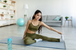 © Prostock-studio - Pretty young Indian woman stretching her legs, exercising during home workout